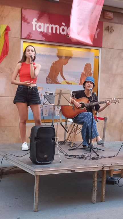 Actuació musical, noia cantant i noi tocant la guitarra