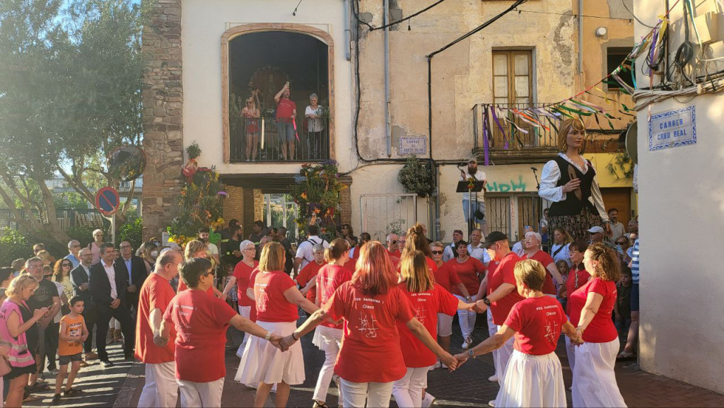 Persones ballant sardanes i fent ofrena floral a la patrona