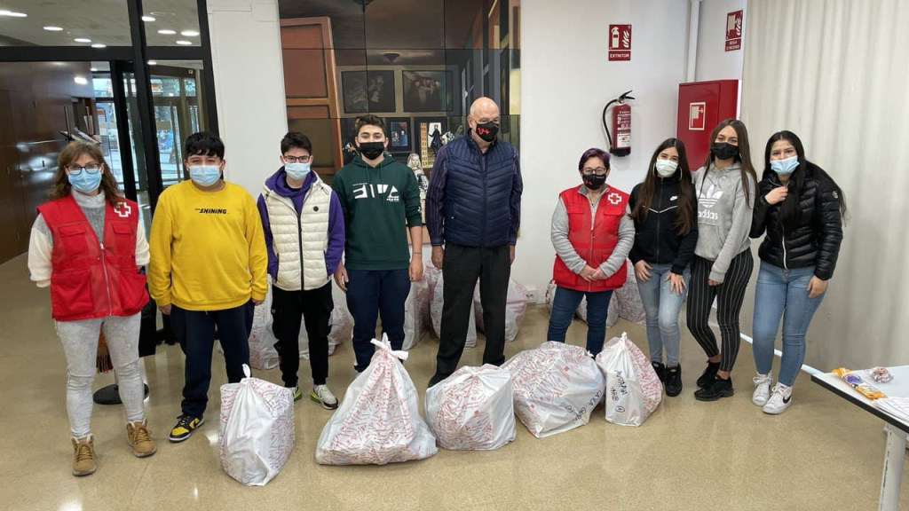 foto de grup a la Casa de cultura de nois i noies voluntaris i el personal de Creu Roja amb les bosses de recollida de joguines