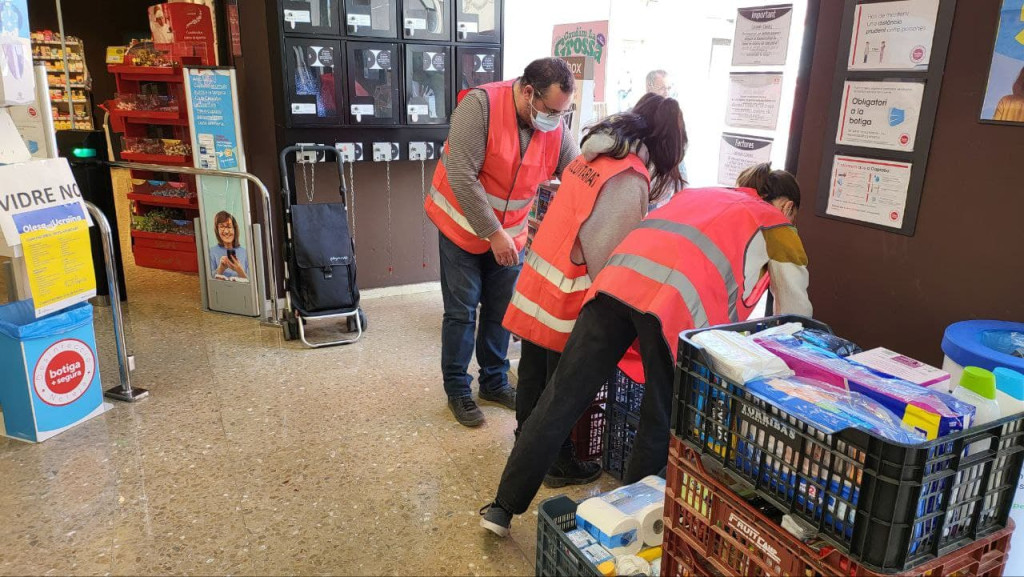 Persones voluntaries recollint material i aliments al supermercat