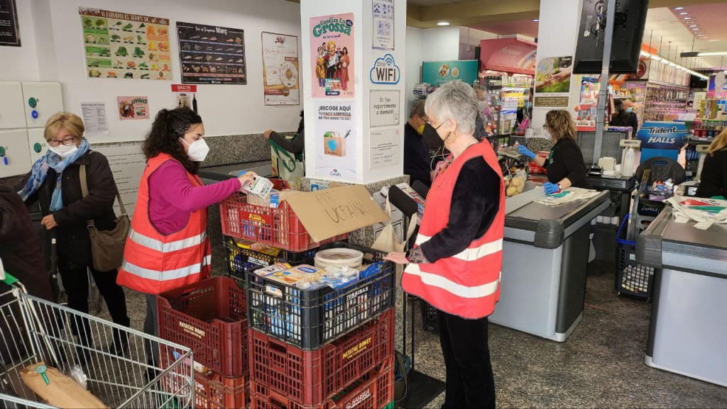 Persones voluntaries recollint material i aliments al supermercat