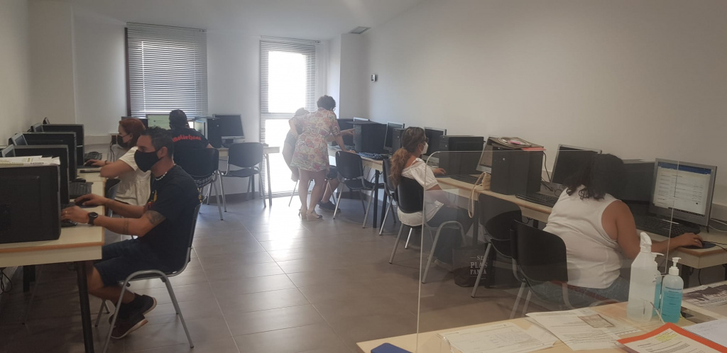 Sala d'ordinadors amb usuaris i usuàries amb una orientadora laboral