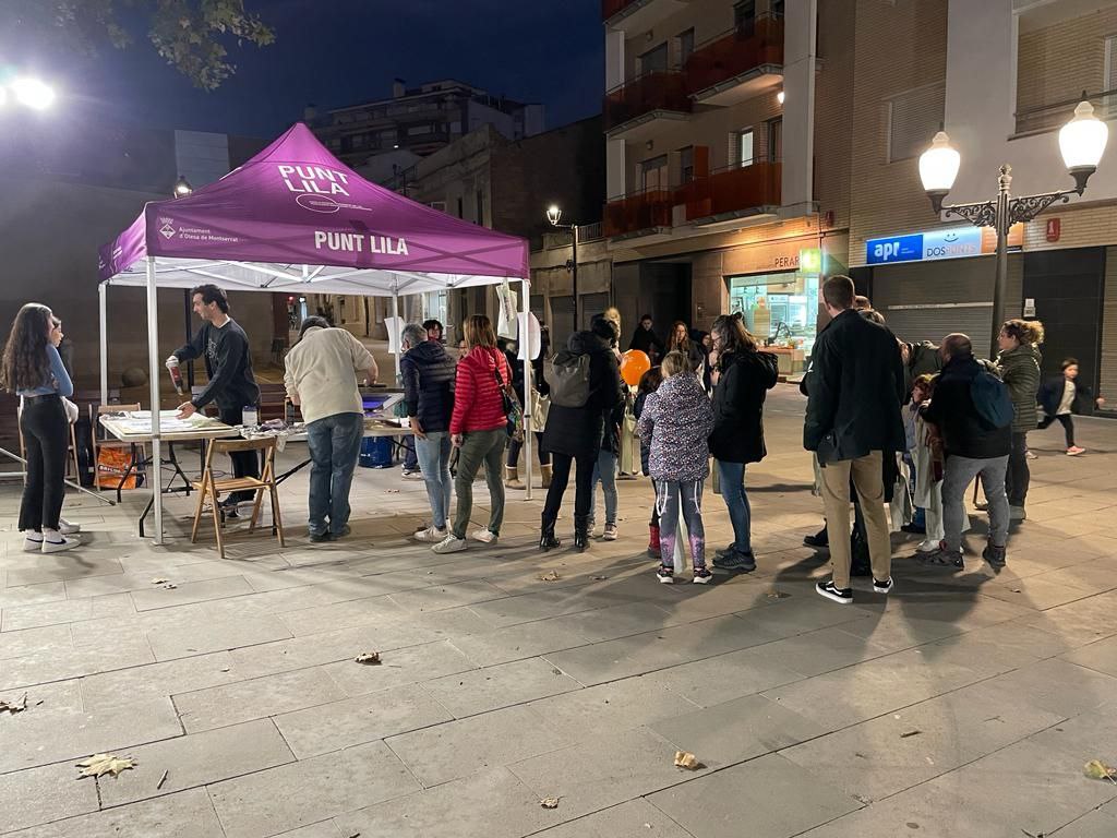 Punt lila davant de l'ajuntament amb cua de persones per recollir la seva bossa