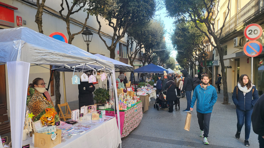 Parada de productes d'artesania i gent passejant i comprant