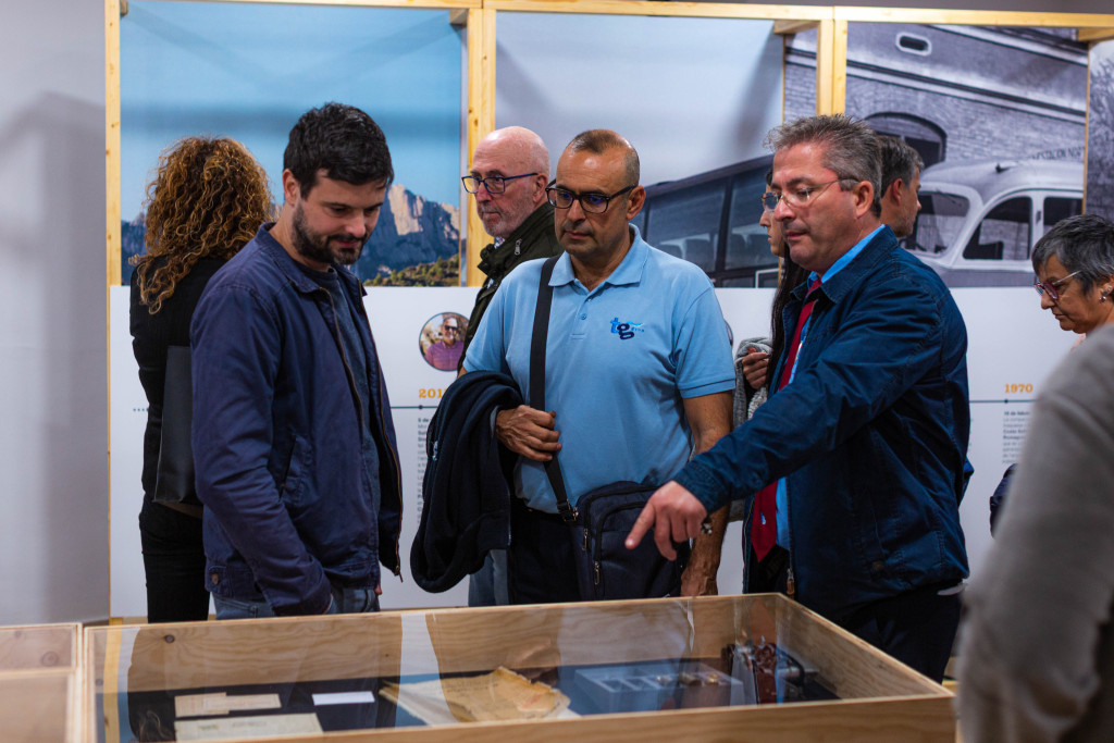 Assistent a l'exposició amb treballadors fent explicació dels panells