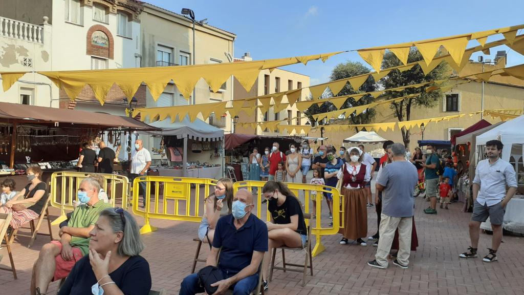 ciutadans passejant pel mercat barroc i asseguts a cadires mirant l'espectacle